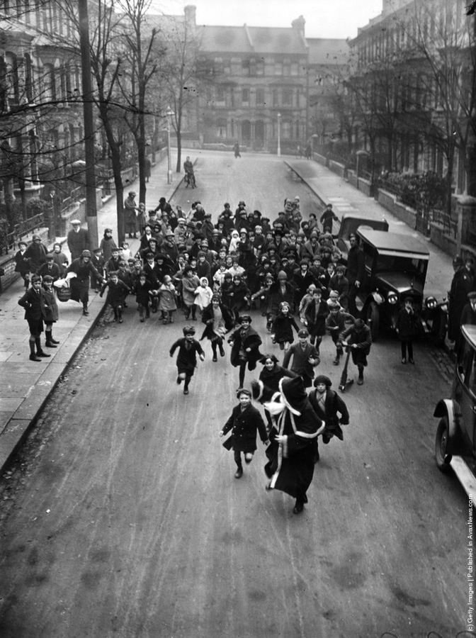 1926-"O multime de copii veseli il urmaresc pe Mos Craciun de-a lungul strazilor Londrei. Acesta se afla in drum spre un magazin din sudul Londrei unde va trebui sa distribuie cadourile." (H. F. Davis/Topical Press Agency/Getty Images).
