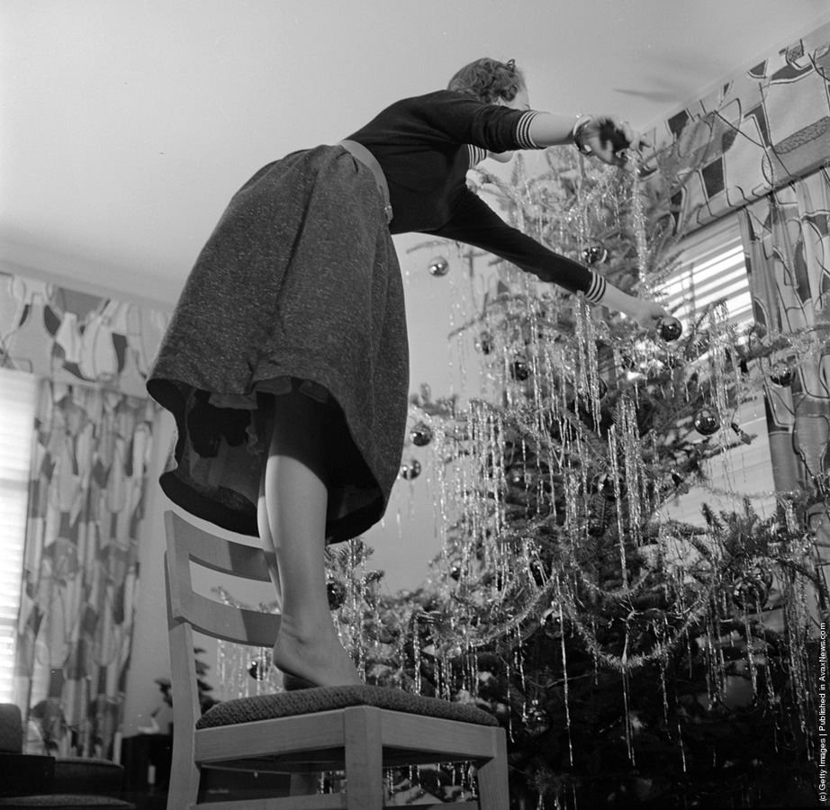 1955-presa vremii ” Când decorați pomul de Crăciun folosiți o scară solidă și nu faceți precum această femeie care stă pe un scaun și se intinde prea departe.” ( Orlando /Three Lions/Getty Images). Circa 1955